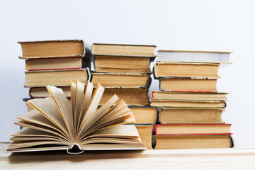 Open book, stack of hardback books on wooden table. Back to school. Copy space