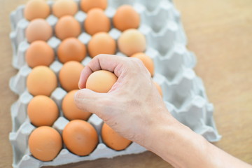 Hand holding egg with de-focus of eggs in paper tray, out of focus selected