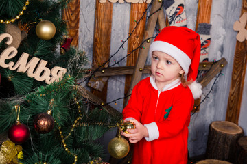 Happy little baby in Santa's costume near Xmas tree