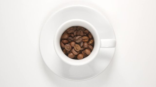 TOP VIEW: Coffee beans in a white cup (stop motion)