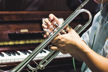 Young man holding a trumpet with piano background