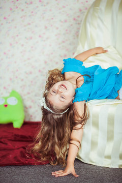 little cute girl in blue shirt lies on white armchair