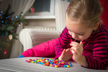 Adorable preschool girl playing with sweets on xmas eve