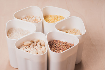 Collection of cereals, grains: rice, oats, buckwheat, millet, wooden table, country kitchen, white capacity,