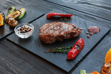 Grilled beef steak closeup on dark wooden table background