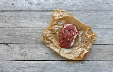 Raw beef steak on dark wooden table background, top view