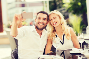 happy couple taking selfie with smatphone at cafe