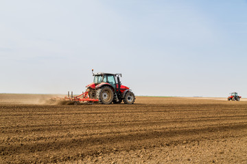 Obraz premium Farmer in tractor preparing land with seedbed cultivator