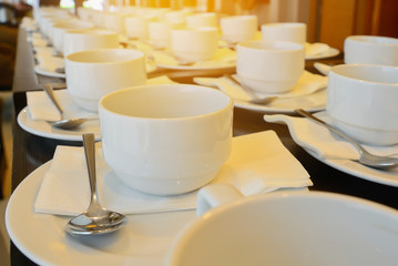Many  white coffee cups  waiting for  serving with warm light ef