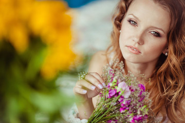 Fototapeta premium beautiful and gentle young woman holds purple flowers in hands