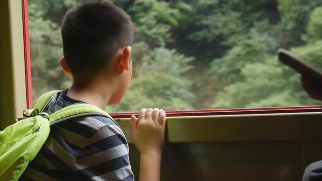 Asian boy looking out window while travel by Sagano Romantic Train, Japan 