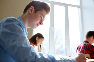 group of students with books writing school test