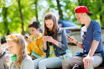 happy teenage friends with smartphones outdoors