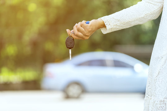 Young woman holding her new car key at Outdoor parking
