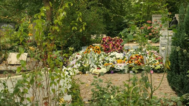 Big pile of colorful flowers on grave, wide