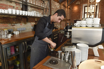 young italian barista or coffee maker at restaurant shop preparing milk cream at cafe machine