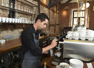 young italian barista or coffee maker at restaurant shop preparing milk cream at cafe machine