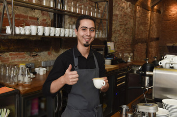 Fototapeta na wymiar young italian barista or coffee maker at restaurant shop preparing milk cream at cafe machine