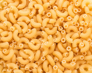 Yellow pasta in form of curved tubes closeup. Texture.