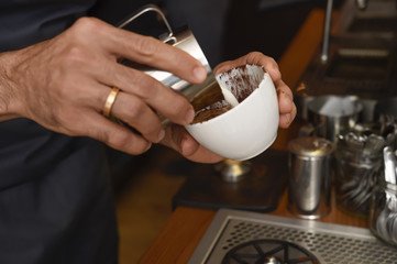 barista preparing coffee cream pouring milk in mug decorating with foam