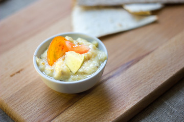 Delicious hummus on wooden board with the vegatables and pieces of bread.
