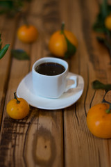 Obraz na płótnie Canvas Small white cup of coffee and mandarins on wooden background