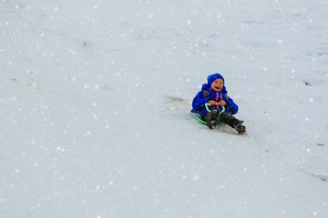 kids winter fun- little boy sliding in snow