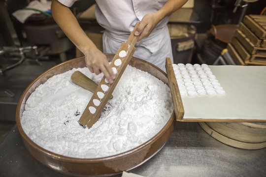 A small artisan producer of wagashi. A woman chef mixing a large bowl of ingredients and pressing the mixed dough into moulds in a commercial kitchen. 