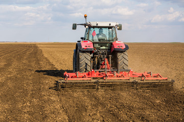 Farmer in tractor preparing land with seedbed cultivator