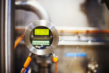Close up of a gauge with a digital print out in a brewery.