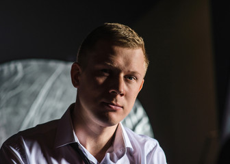 Low key portrait of serious fair man in classic clothes