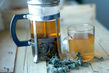 Green herbal tea in a teapot and cup on a wooden background.