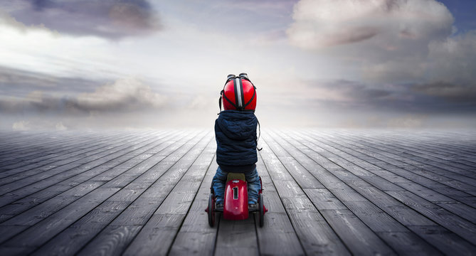 kleiner Junge auf Rutschauto schaut neugierig in die Zukunft