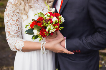 Elegant young bride and groom posing together for photo outdoors on wedding day. Close up of anonymous wedding couple holding hands and hugging. Horizontal color portrait of just married people.