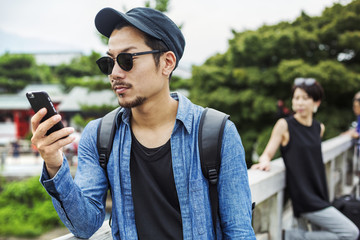 A man looking at his smart phone, a woman behind him.
