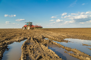 Fototapeta premium Farmer in tractor preparing land with seedbed cultivator