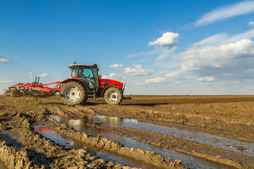 Obraz premium Farmer in tractor preparing land with seedbed cultivator