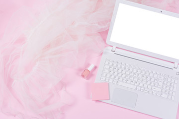 White laptop, notes, nail polish and tulle on pink background