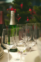 bottle of champagne and wine glasses on the background of the Christmas tree, blurred bokeh. the atmosphere of the New Year holiday table, anticipation. Festive table appointments