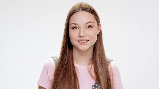 Surprised young beautiful girl smiling over white background. Slow motion.