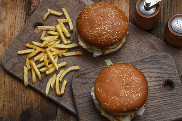 Beef burgers and french fries on wooden background with blank sp