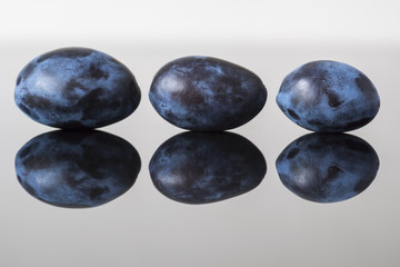 ripe juicy plum on black glass desk