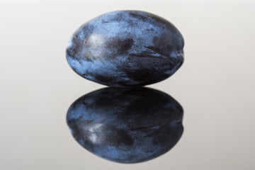 ripe juicy plum on black glass desk