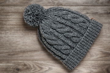 Knitted winter hat on a wooden background