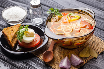 Fresh vegetable soup with noodles in a pot on black