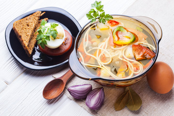 Fresh vegetable soup with noodles in a pot on white