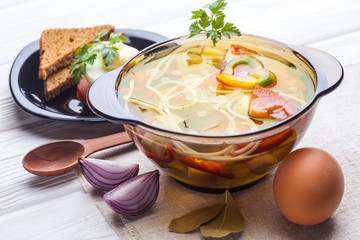 Fresh vegetable soup with noodles in a pot on white
