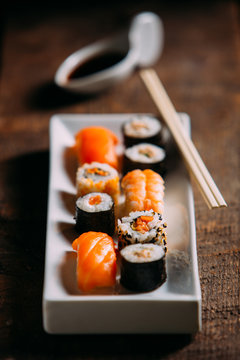 Sushi maki rolls and sashimi on a wooden background