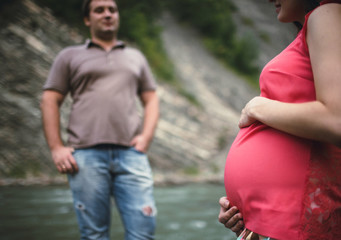 Beautiful pregnant woman with her husband near the river