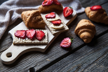 A delicious breakfast of strawberries and bread on wooden background. Fruit, food, sandwiches, cheese. Vintage style.